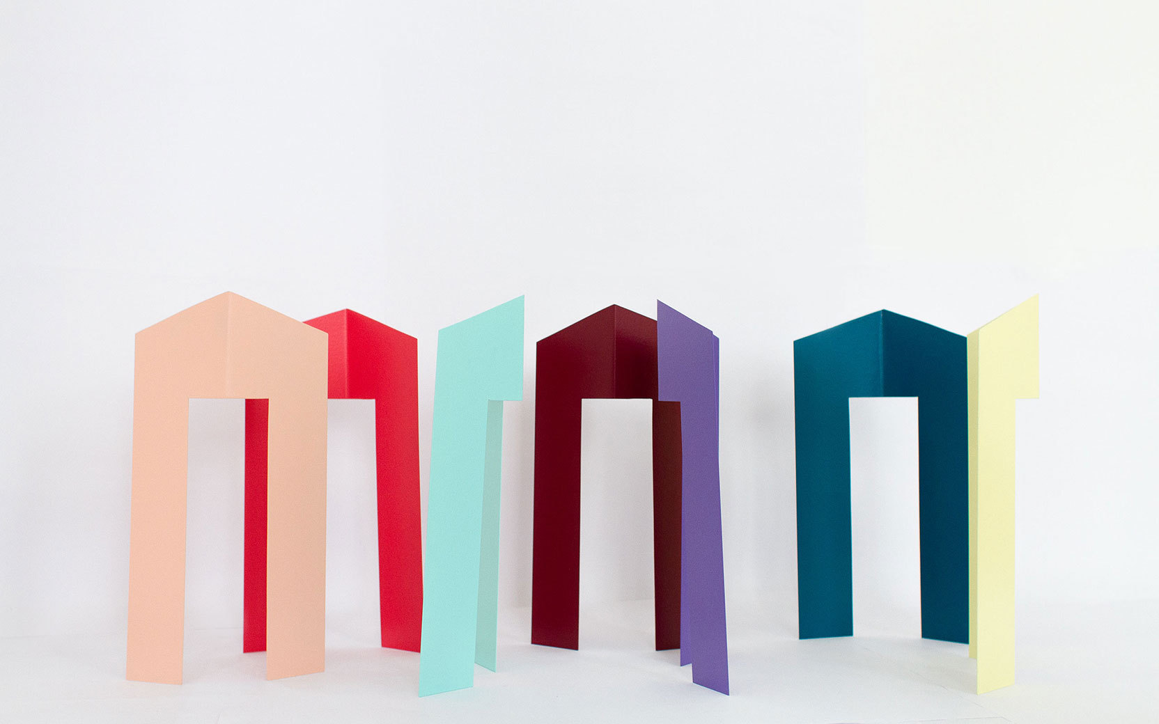 Row of tall pastel-colored arch-shaped panels standing upright on a white surface.