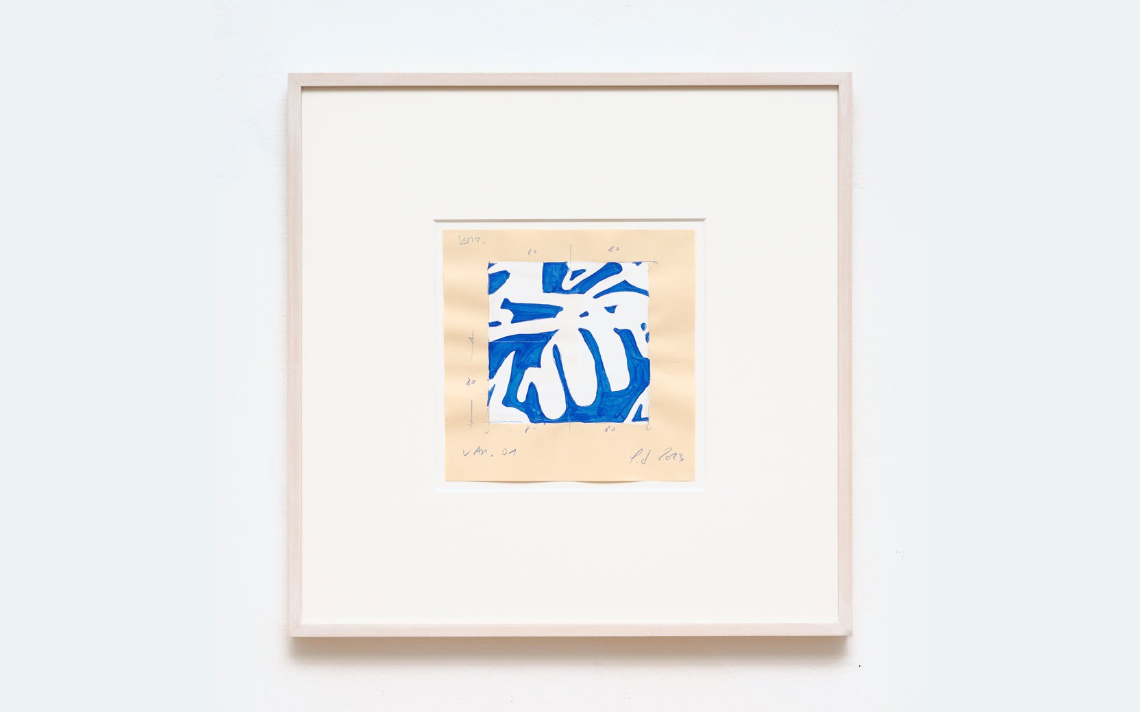 Framed abstract blue motif on beige paper, mounted on a white mat inside a light-wood frame on a pale wall.